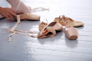 Ballerina's slippers lying on the floor while she is trying them on
